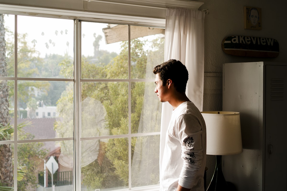 A man alone at a window in morning light after the end of a long relationship